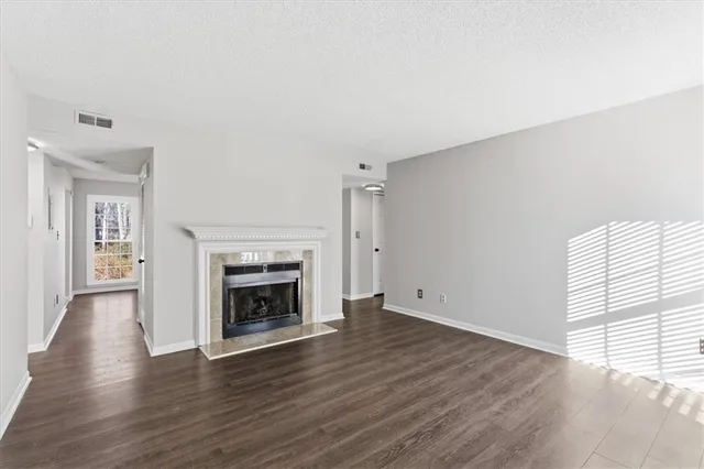 an empty room with wooden floor fireplace and windows