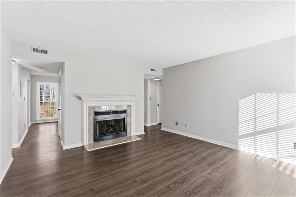 1166 Booth Road Southwest, Unit 906 Marietta, GA 30008 - Photo 2 of 27 an empty room with wooden floor fireplace and windows