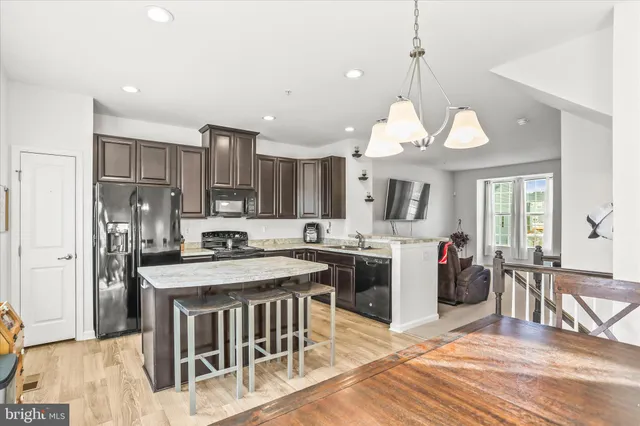 a kitchen with stainless steel appliances granite countertop a stove oven a refrigerator a sink dishwasher and a dining table with wooden floor