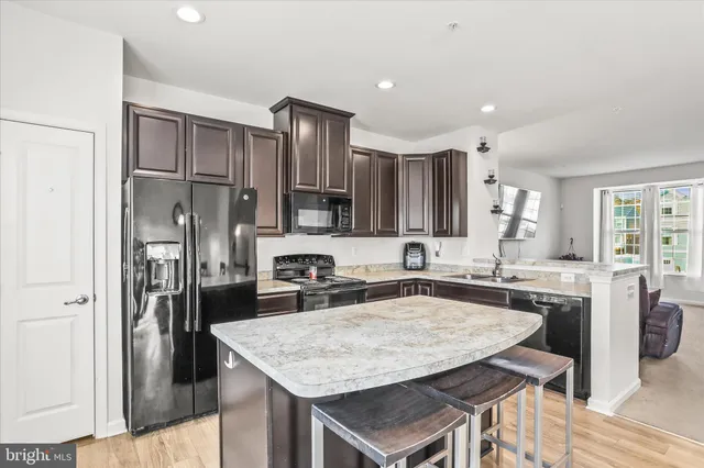 a kitchen with stainless steel appliances granite countertop a kitchen island a stove a refrigerator a sink a dining table and chairs