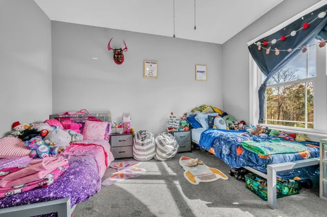 a spacious bedroom with a bed a chandelier and windows