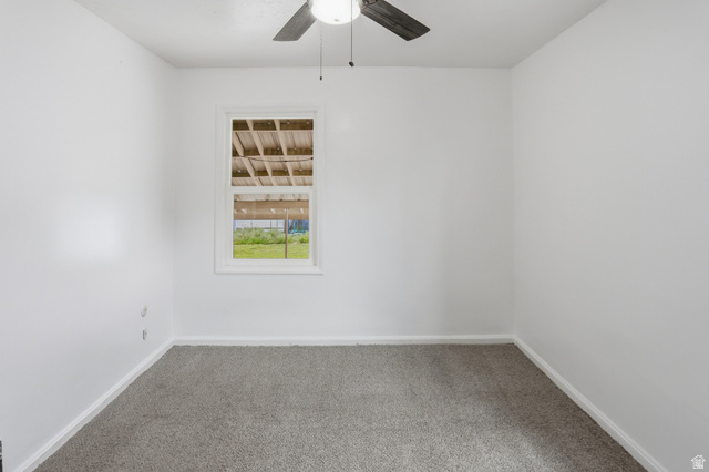 774 37th Street South Ogden, UT 84403 - Photo 16 of 47 Room featuring light gray carpeting, crisp white walls, a white-framed window, and a ceiling fan with dark wood-finish blades