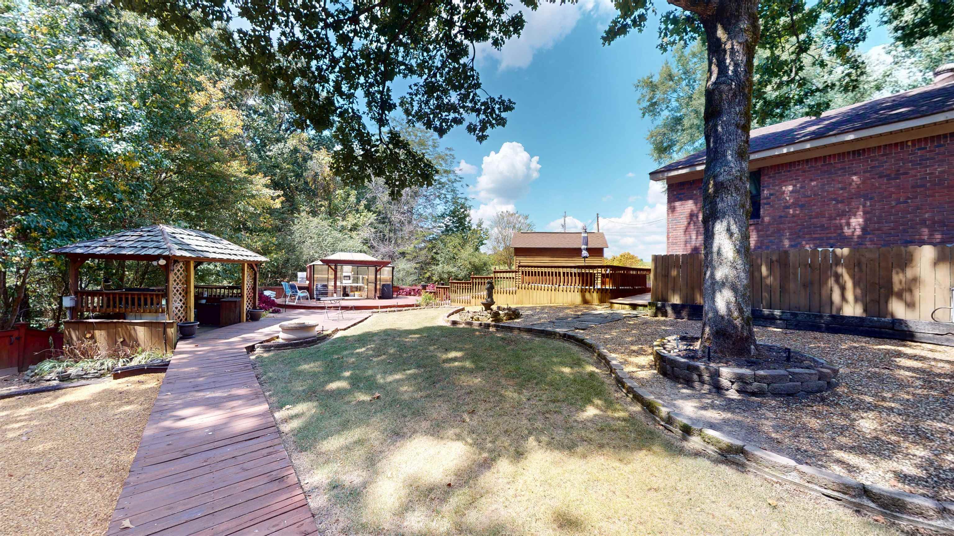 420 Joann Road Somerville, TN 38068 - Photo 29 of 40 Wood-finish walkway leading to a hexagonal gazebo, a secondary round deck with another gazebo, and an expansive lawn area