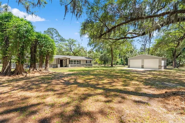 a front view of a house with a garden and trees