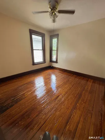 an empty room with wooden floor chandelier and windows