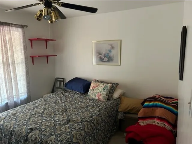a bedroom with a bed and a chandelier fan