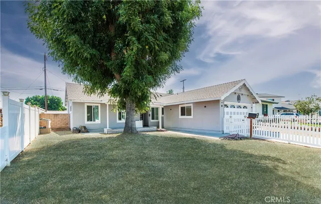 a front view of house with yard and trees in the background