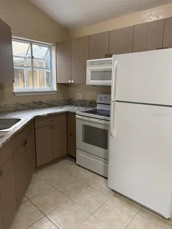 a white refrigerator freezer sitting inside of a kitchen with stainless steel appliances granite countertop a stove a refrigerator and a sink