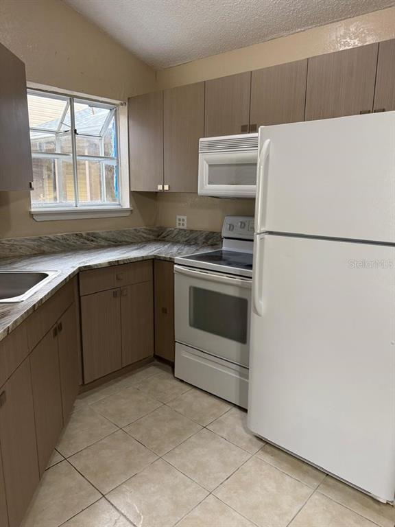 1908 Lake Atriums Circle, Unit 12 Orlando, FL 32839 - Photo 5 of 11 a white refrigerator freezer sitting inside of a kitchen with stainless steel appliances granite countertop a stove a refrigerator and a sink