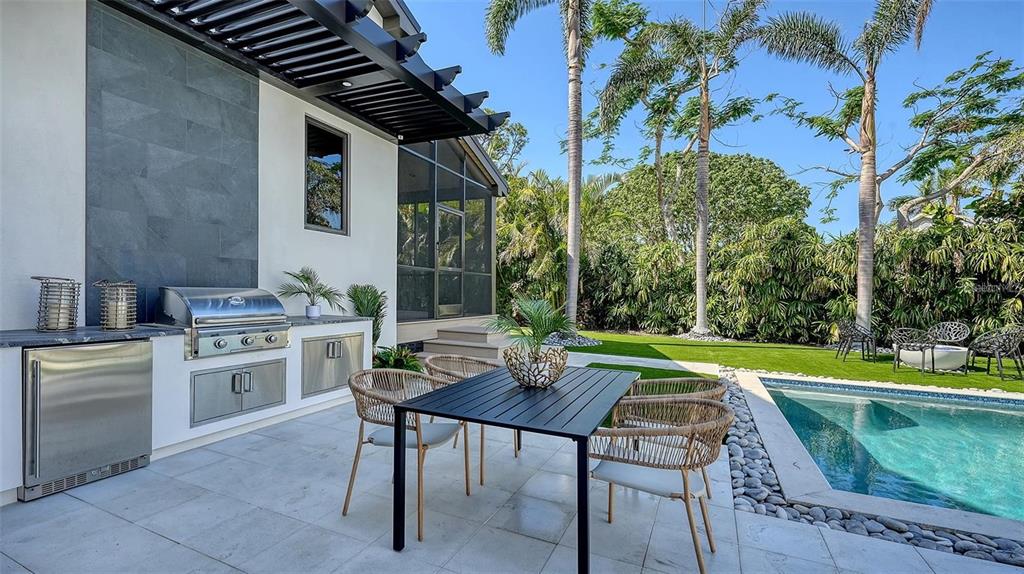 5035 Bay Shore Road Sarasota, FL 34234 - Photo 47 of 84 a patio with a table and chairs and a barbeque