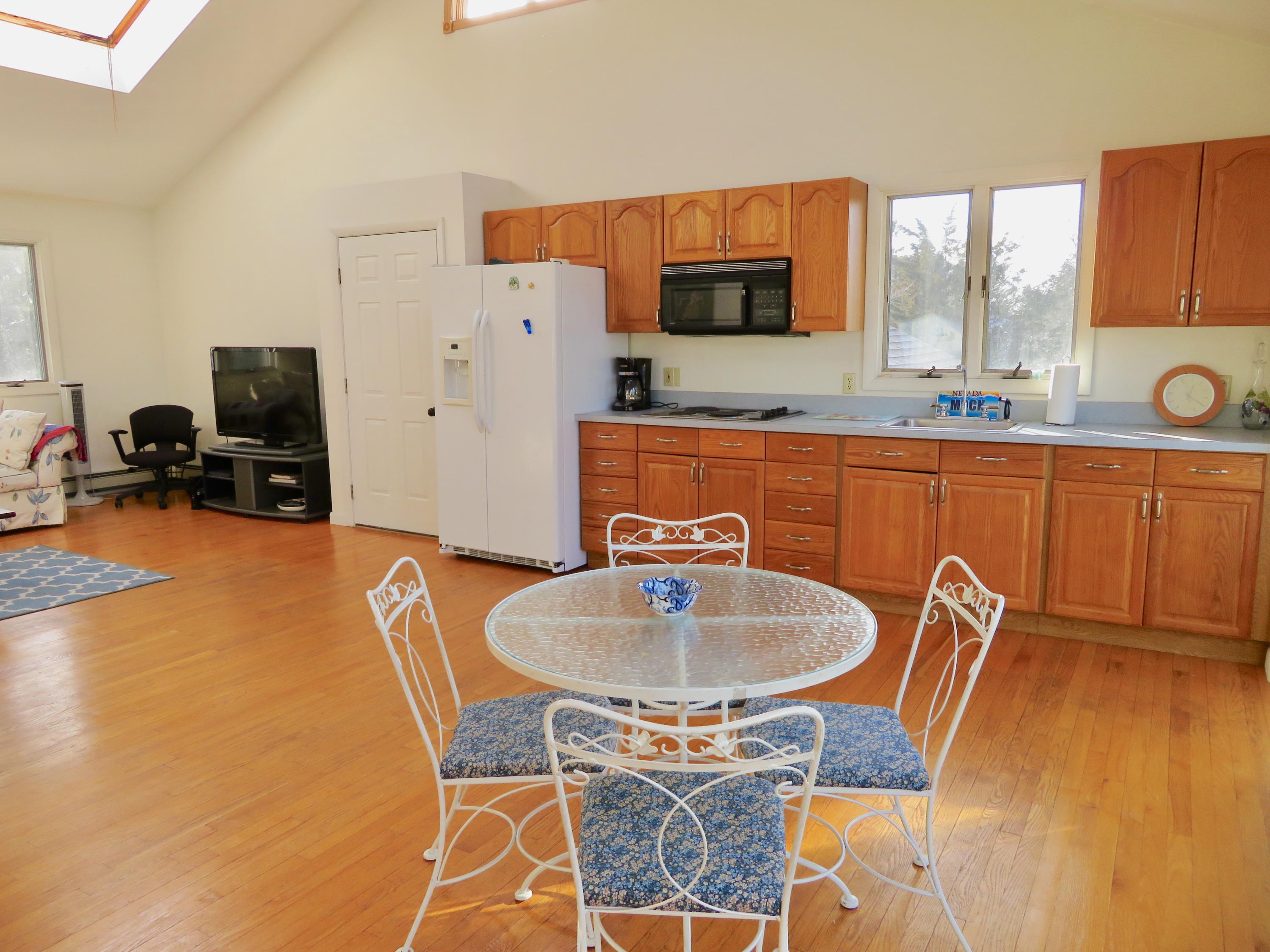 111 Elgin Road Pocasset, MA 02559 - Photo 19 of 34 a kitchen with stainless steel appliances granite countertop a sink a stove a dining table and chairs with wooden floor
