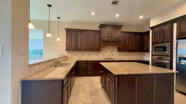 a kitchen with kitchen island granite countertop wooden cabinets a refrigerator and granite counter tops