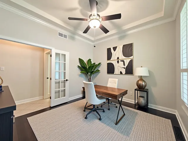 an empty room with wooden floor chandelier fan and windows