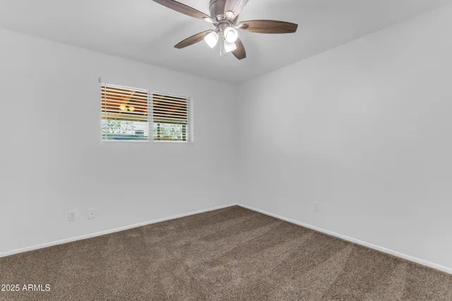an empty room with a window and a ceiling fan