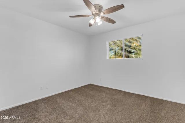 an empty room with a window and a ceiling fan