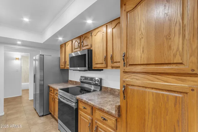 a kitchen with stainless steel appliances granite countertop a sink a stove and a refrigerator with wooden floor