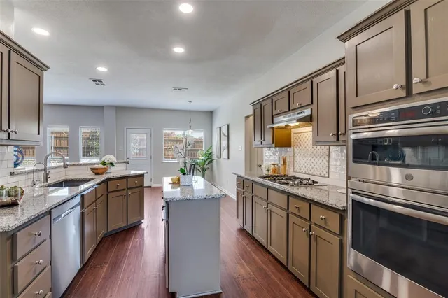 a kitchen with stainless steel appliances granite countertop a stove a sink and a refrigerator