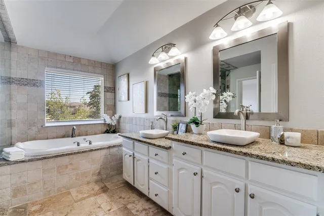 a bathroom with double vanity sinks a large mirror and a bathtub