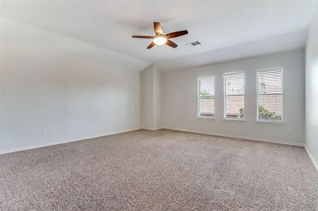 an empty room with ceiling fan and windows