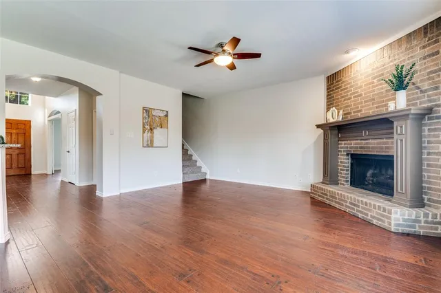 a view of an empty room with wooden floor fireplace and a window
