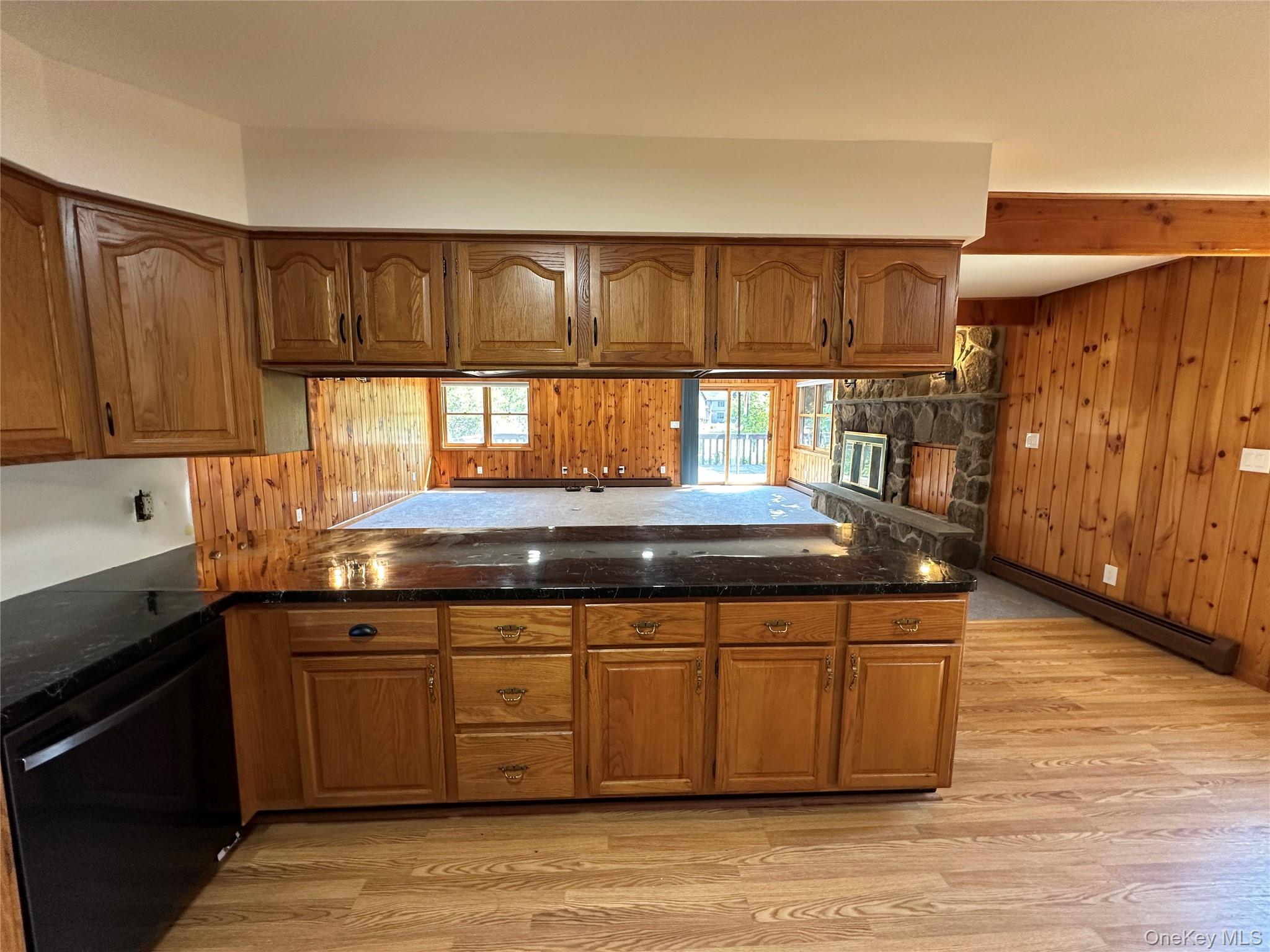 250 Rockland Road Roscoe, NY 12776 - Photo 20 of 32 Kitchen featuring brown cabinetry, black dishwasher, wooden walls, light wood-type flooring, and beam ceiling