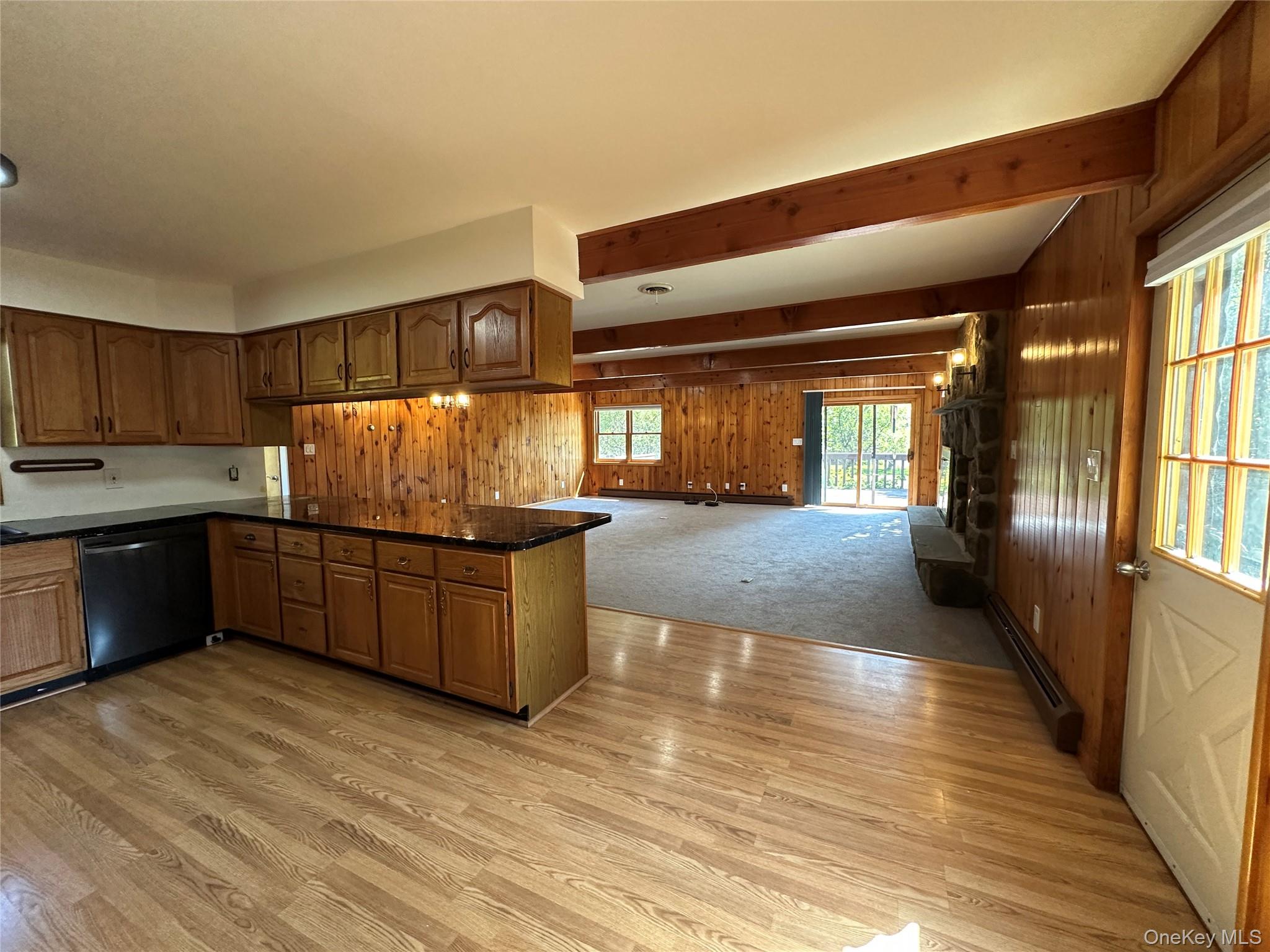250 Rockland Road Roscoe, NY 12776 - Photo 21 of 32 Kitchen featuring wood walls, beam ceiling, dishwasher, brown cabinetry, and a baseboard radiator