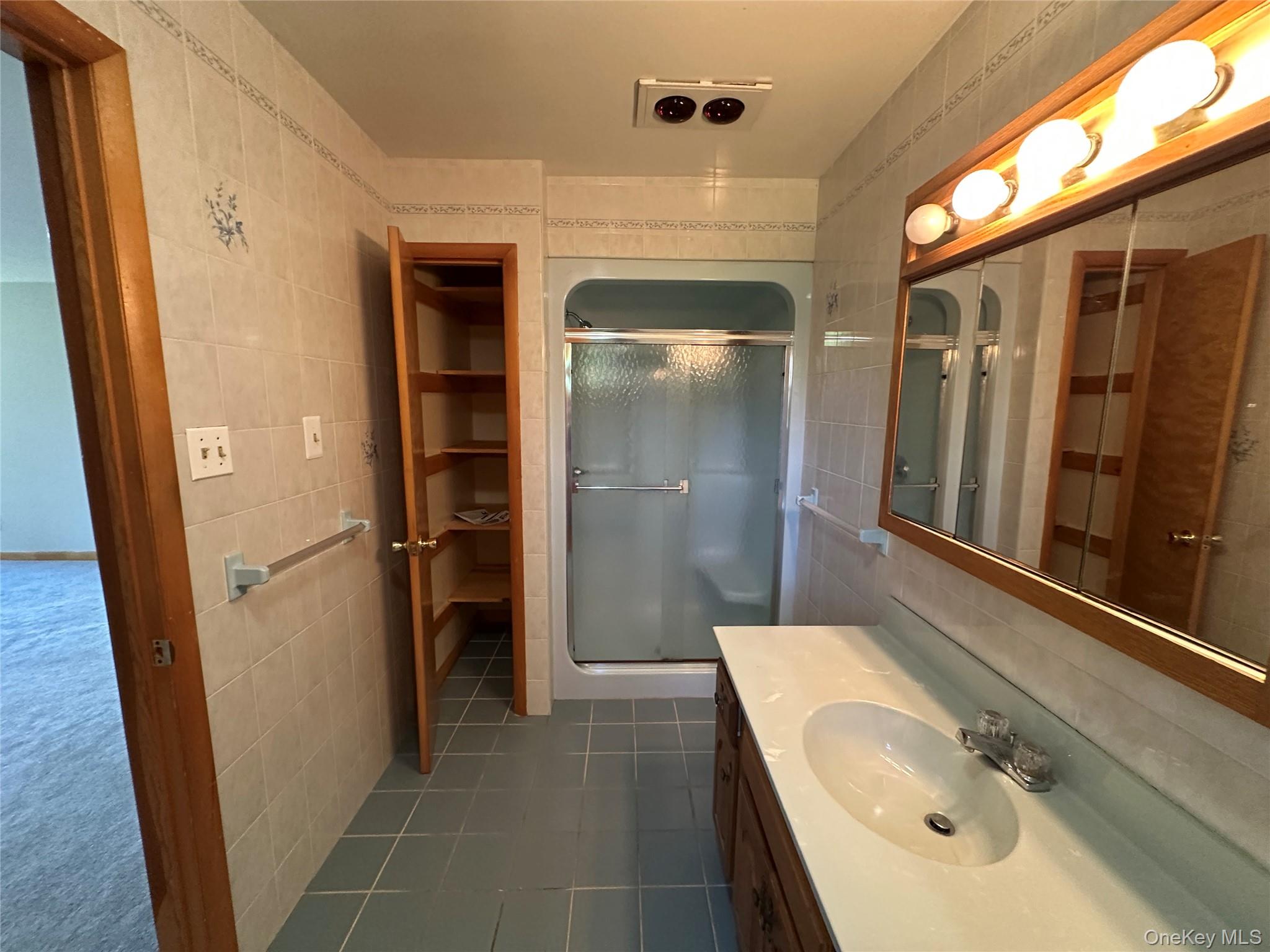 250 Rockland Road Roscoe, NY 12776 - Photo 32 of 32 Bathroom featuring vanity, dark tile patterned flooring, a stall shower, and tile walls