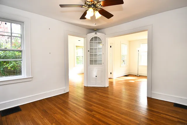 a view of empty room with wooden floor and fan
