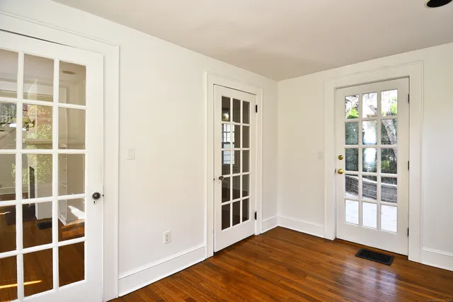 a view of an empty room with wooden floor and windows