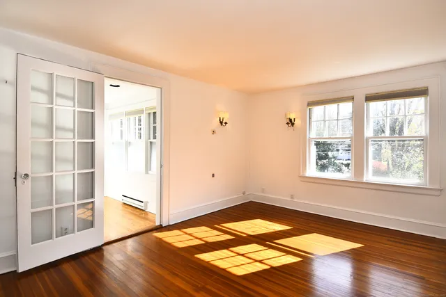an empty room with wooden floor and windows