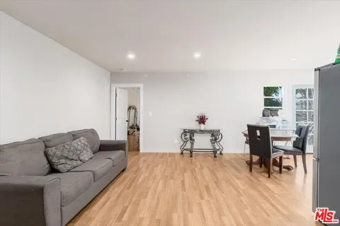 a living room with furniture and a dining table with wooden floor