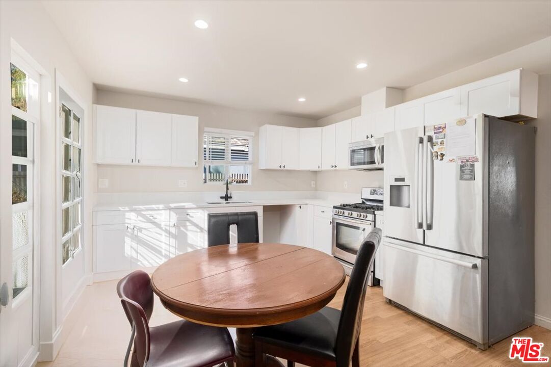 1206 West Magnolia Street Compton, CA 90220 - Photo 7 of 40 a kitchen with refrigerator a stove and wooden floor