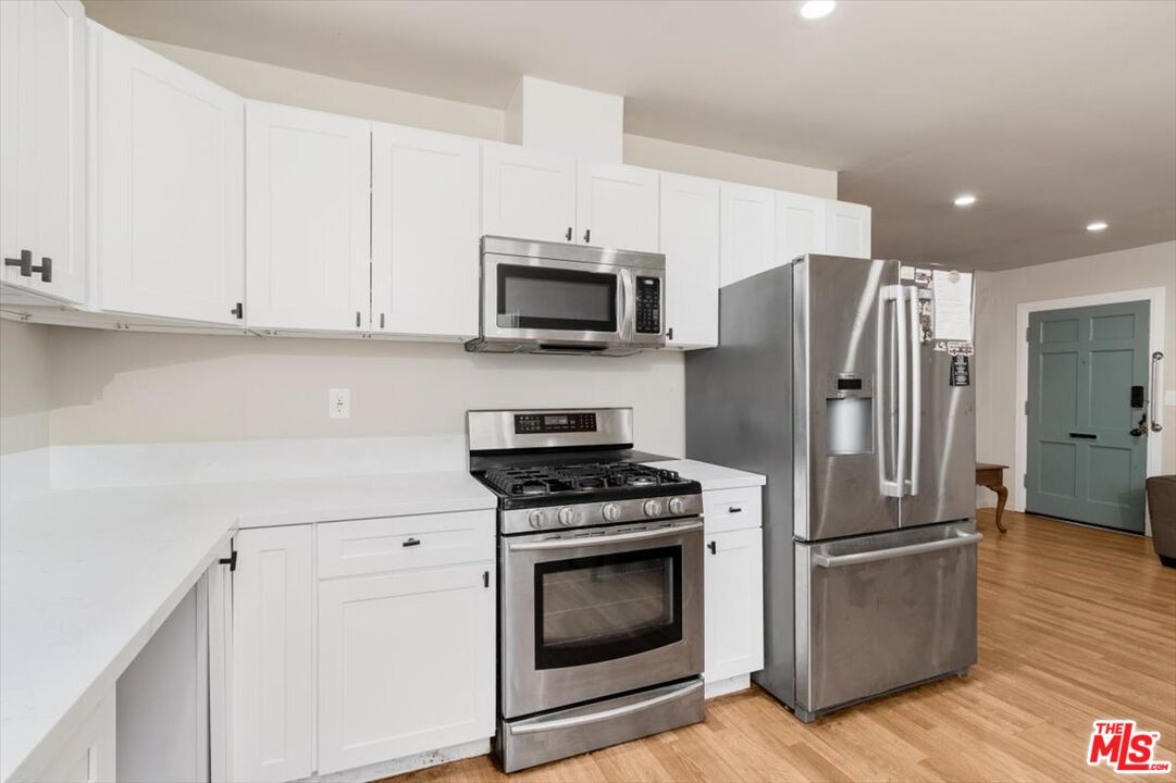 1206 West Magnolia Street Compton, CA 90220 - Photo 10 of 40 a kitchen with granite countertop a refrigerator stove and wooden cabinets