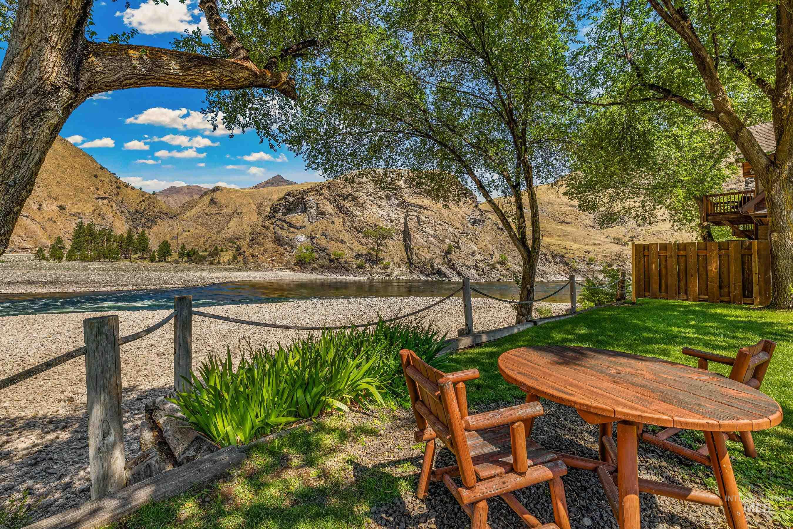 1432 Salmon Drive Riggins, ID 83549 - Photo 33 of 39 Riverside property featuring a spacious lawn area, mature shade trees, and a distant mountain backdrop