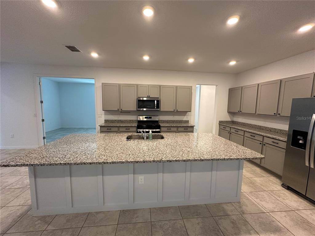7526 Southwest 65th Place Road Ocala, FL 34474 - Photo 10 of 28 a large kitchen with kitchen island granite countertop a sink a counter top space appliances and cabinets
