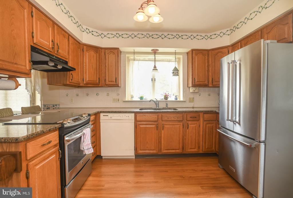 2 Battle Drive Newark, DE 19702 - Photo 11 of 35 a kitchen with stainless steel appliances granite countertop a refrigerator a sink dishwasher a stove with wooden cabinets and floor