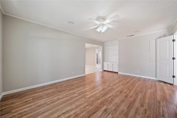 a view of an empty room with wooden floor and a window