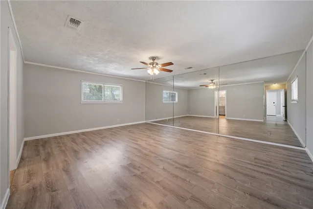 a view of empty room with wooden floor and fan