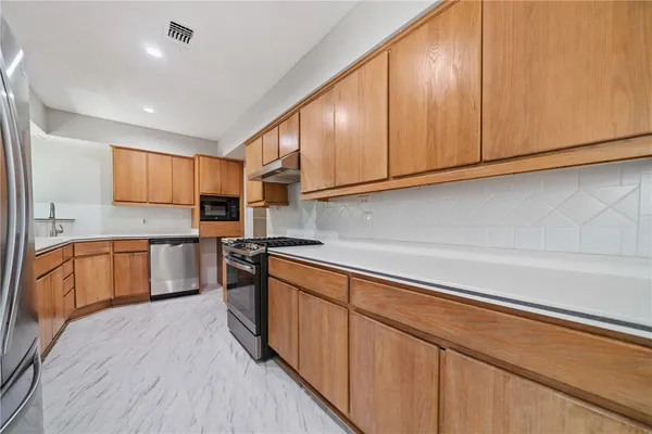 a kitchen with stainless steel appliances granite countertop a stove a sink and a refrigerator