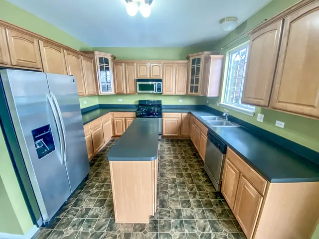 a kitchen with stainless steel appliances granite countertop a refrigerator a stove top oven a sink and dishwasher