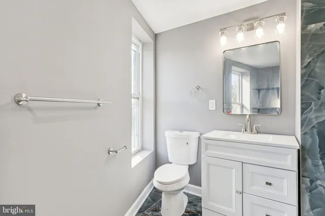 a bathroom with a toilet sink vanity and mirror