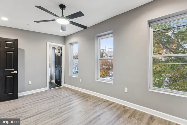 a view of an empty room with a window and wooden floor