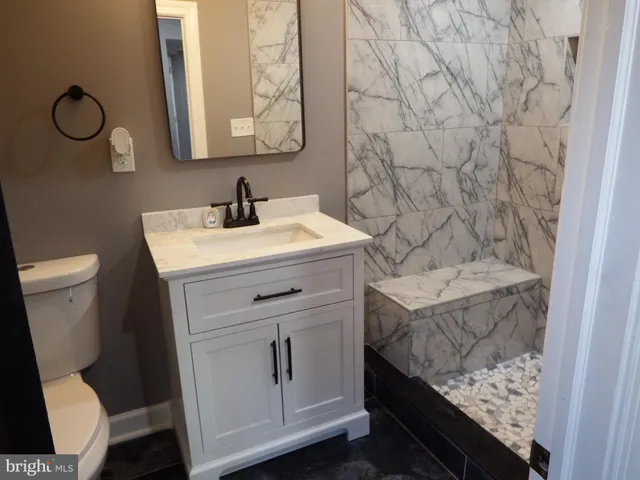 a bathroom with a granite countertop toilet sink and mirror