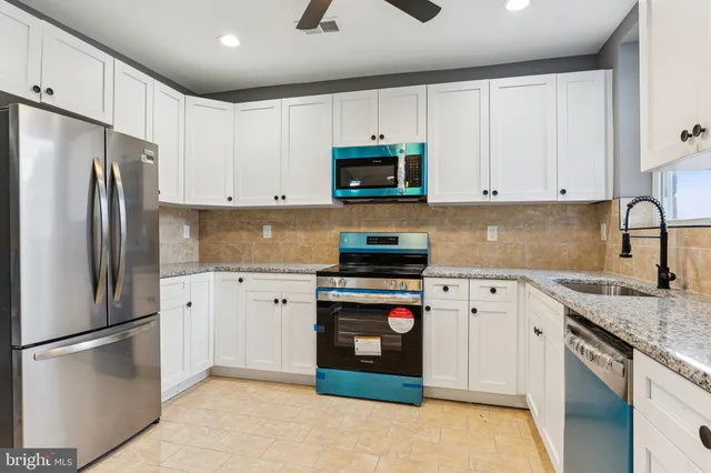 a kitchen with stainless steel appliances granite countertop a refrigerator sink and stove
