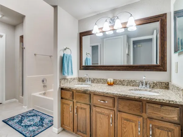 a bathroom with a granite countertop sink a large mirror and a shower