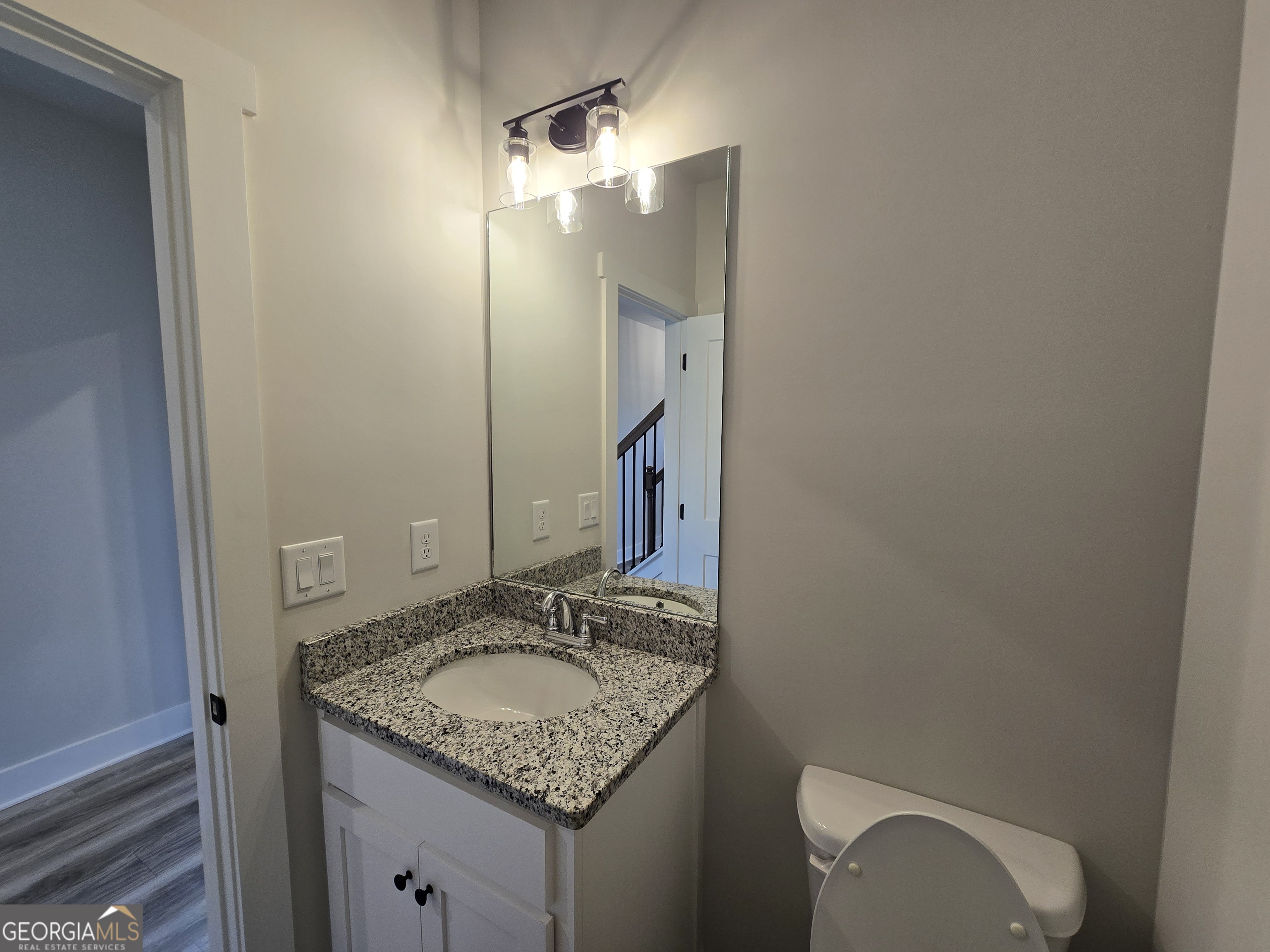1041 Alaina Avenue, Unit 69 Madison, GA 30650 - Photo 7 of 20 a bathroom with a granite countertop sink and a mirror