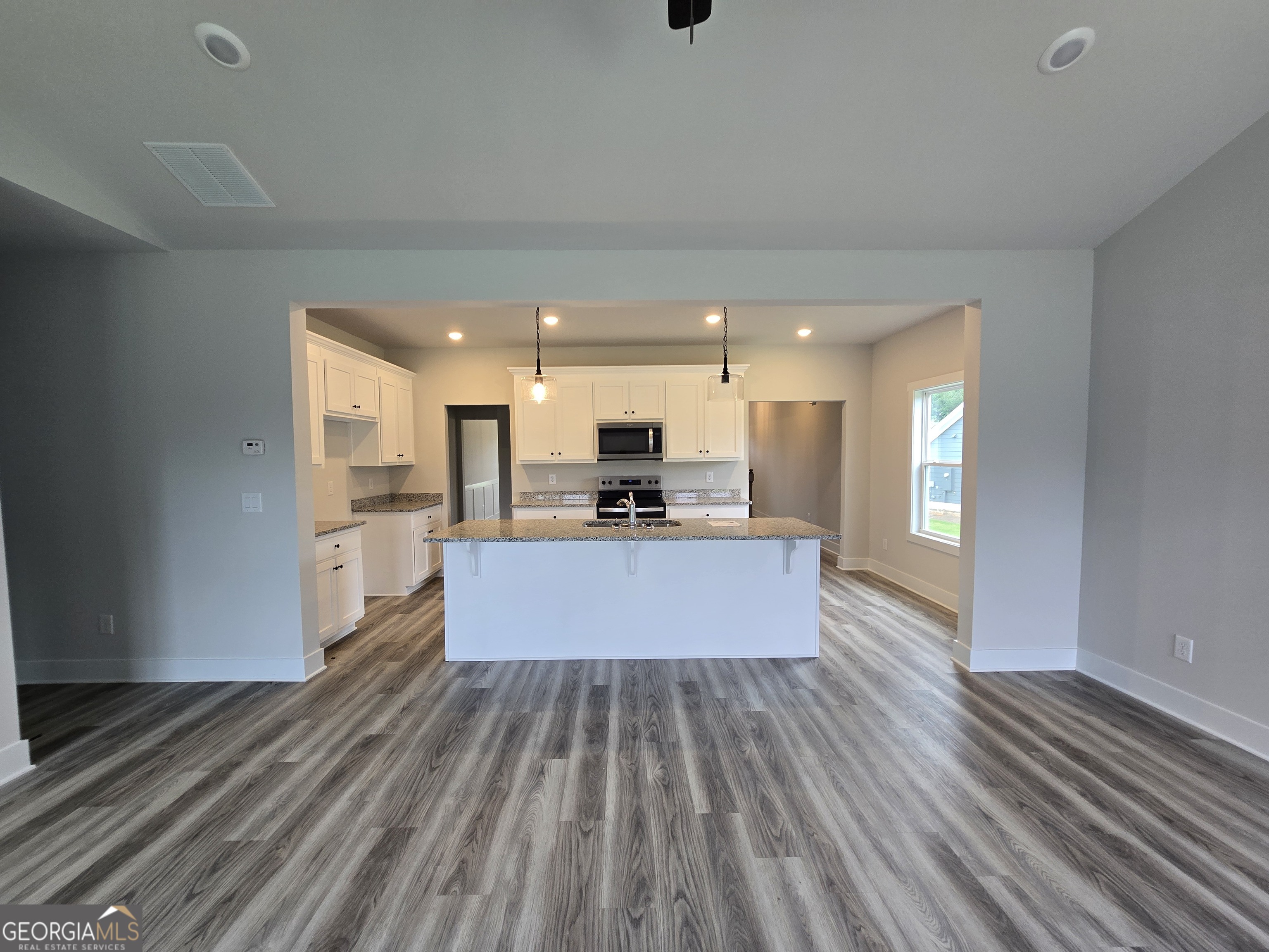 1041 Alaina Avenue, Unit 69 Madison, GA 30650 - Photo 8 of 20 a large white kitchen with kitchen island a sink wooden floor and stainless steel appliances