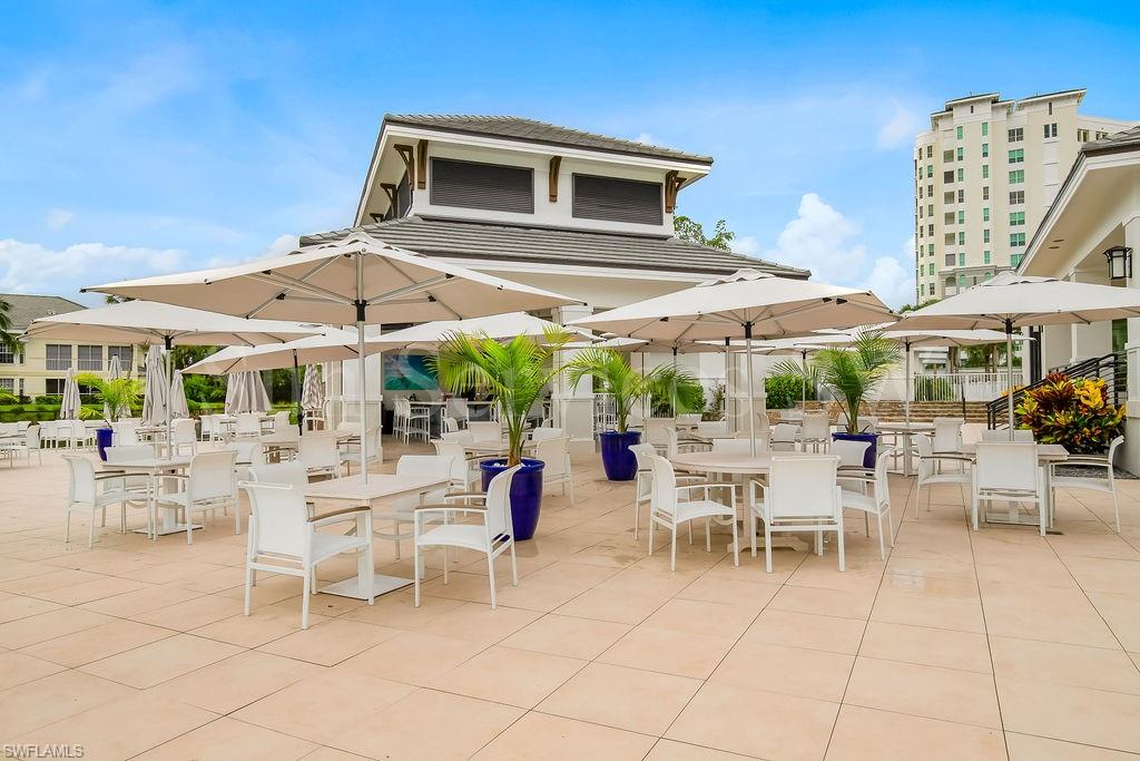 300 Dunes Boulevard, Unit 605 Naples, FL 34110 - Photo 28 of 37 a patio with a table and chairs under an umbrella