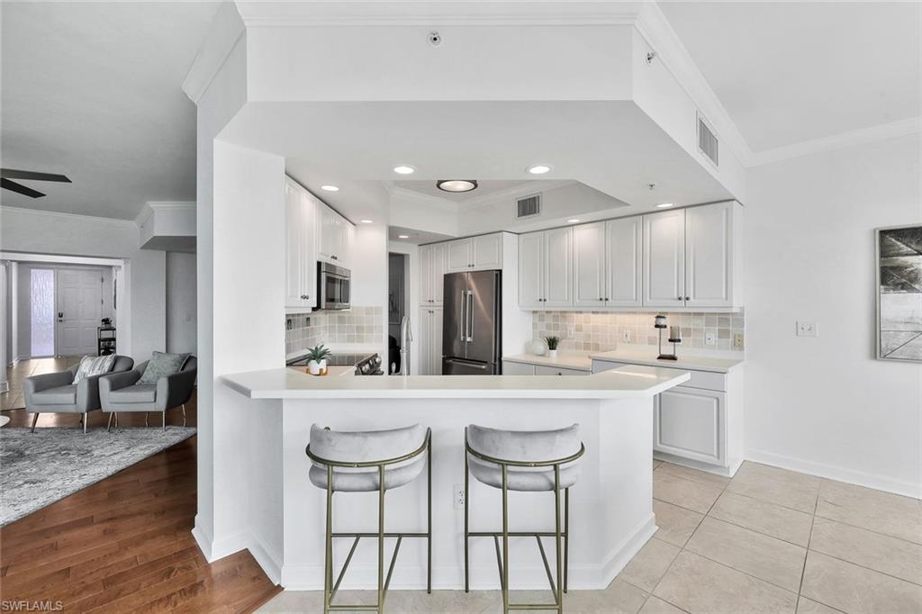 300 Dunes Boulevard, Unit 605 Naples, FL 34110 - Photo 7 of 37 a kitchen with stainless steel appliances kitchen island granite countertop a sink and cabinets
