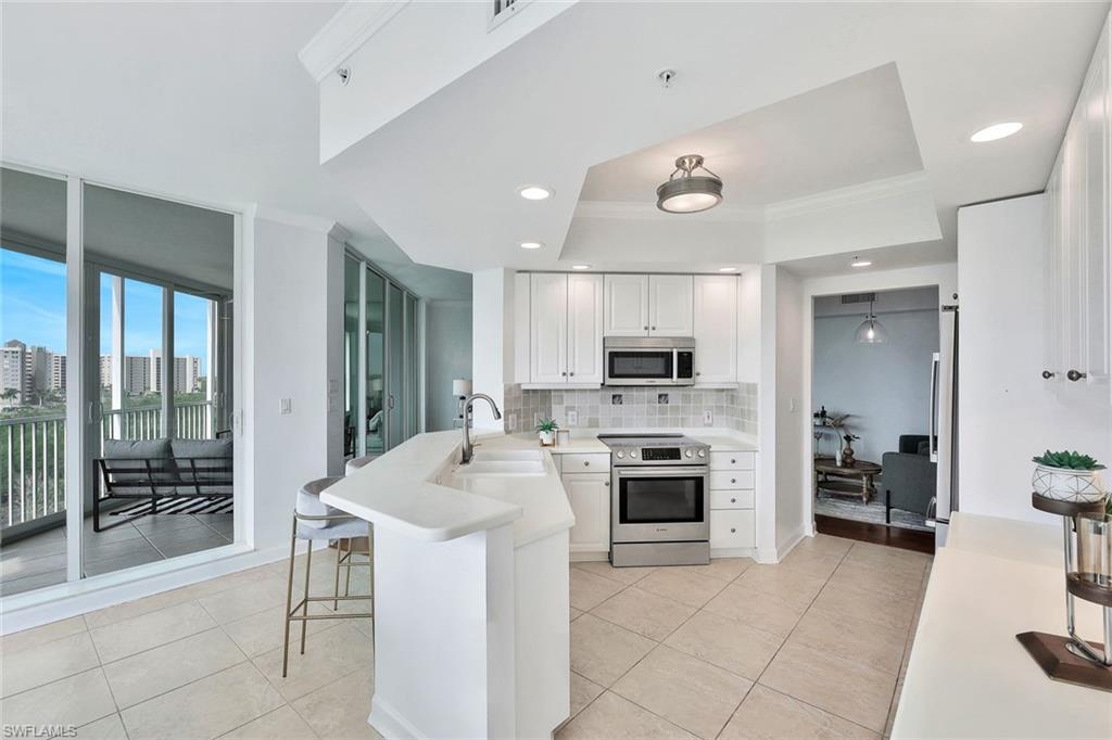 300 Dunes Boulevard, Unit 605 Naples, FL 34110 - Photo 8 of 37 a kitchen with a sink a stove and chairs